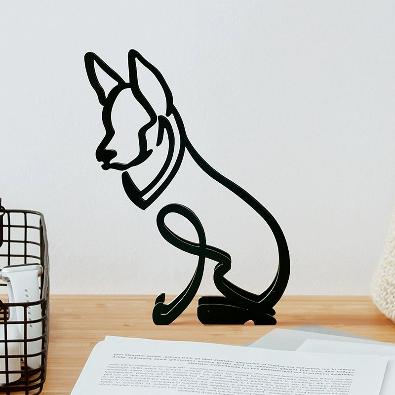 Black metal sculpture of a dog on a wooden surface with a white wall background