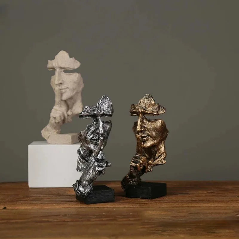Two metallic sculptures on a wooden surface with a gray background