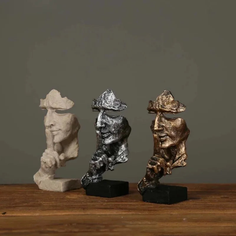 Three decorative sculptures on a wooden surface with a dark background
