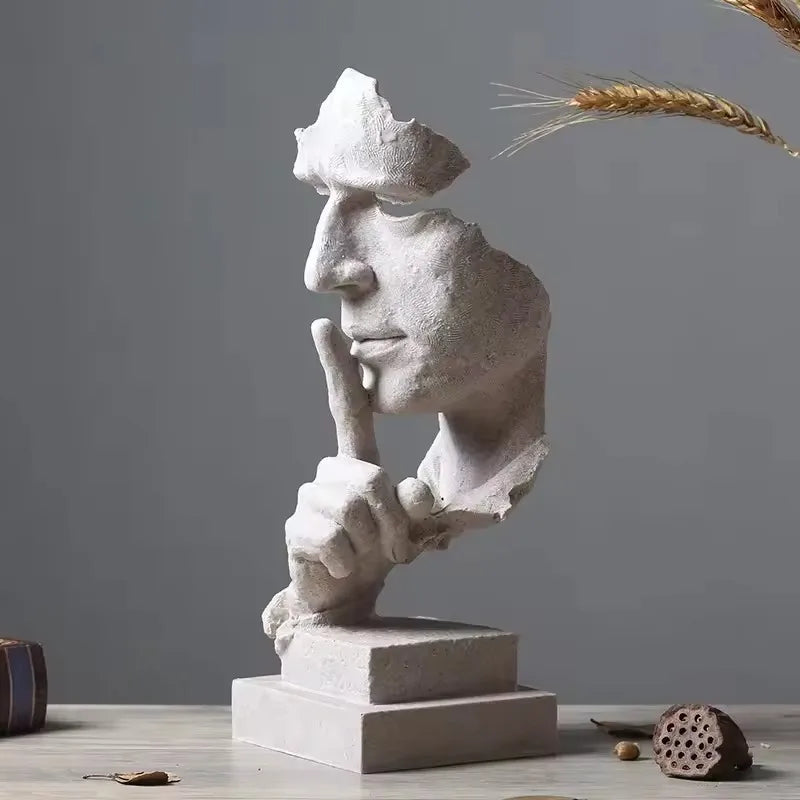 White stone sculpture with a finger raised in a "shushing" gesture on a gray background