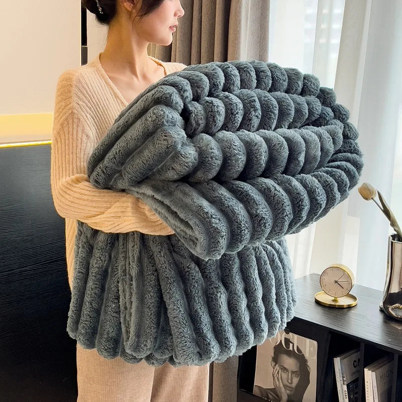 Person holding a large, fluffy gray blanket in a room with a window and desk.