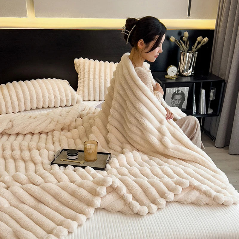 Woman wrapped in a fluffy white blanket on a bed in a cozy room.