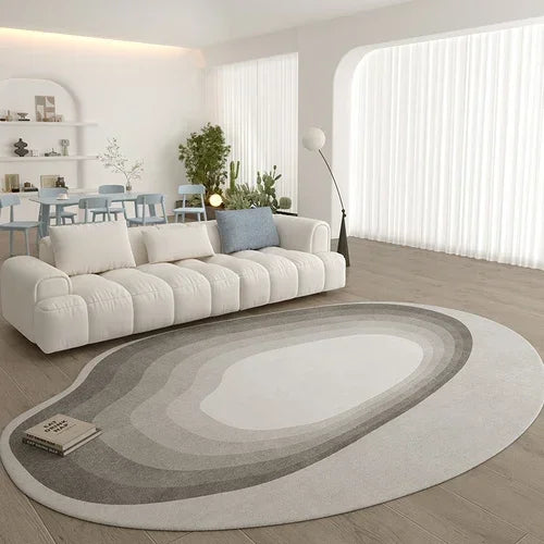 Modern living room with a large gradient white to gray rug, beige sofa, and decorative wall art.