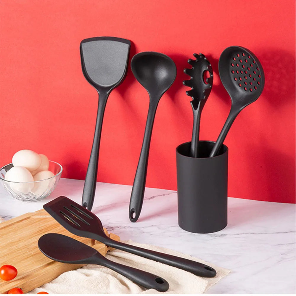 Set of black kitchen utensils including spatulas and ladles on a red background