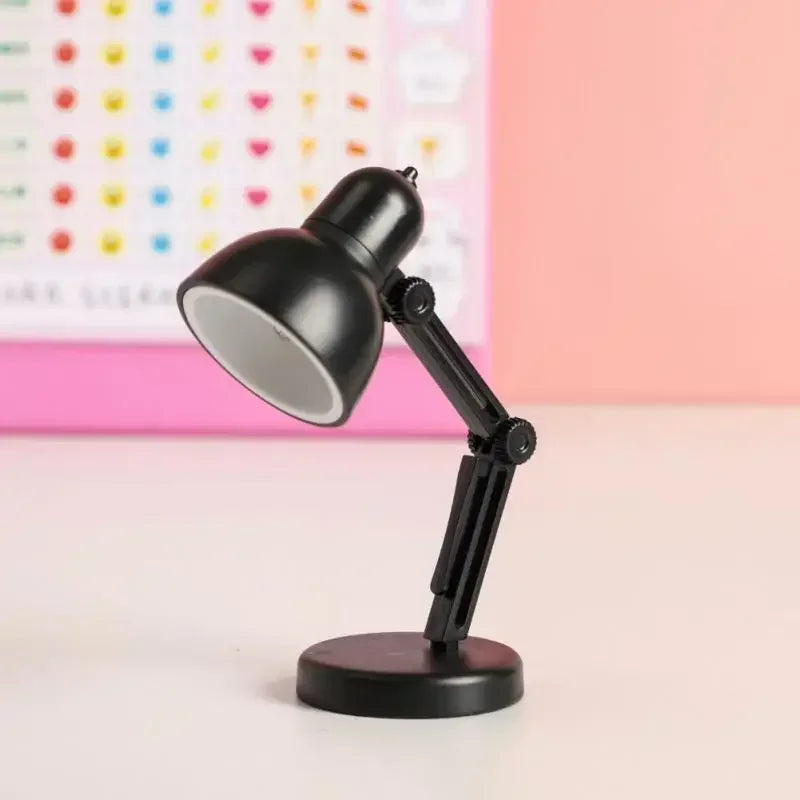 Black desk lamp on a light pink surface with a colorful heart-patterned background