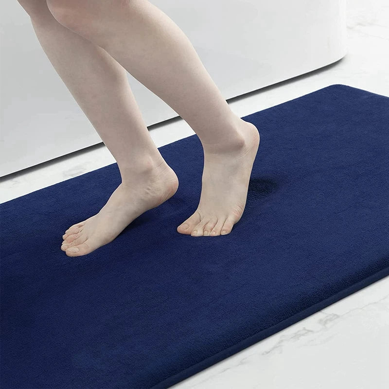 Person stepping onto a blue bath mat with a neutral background