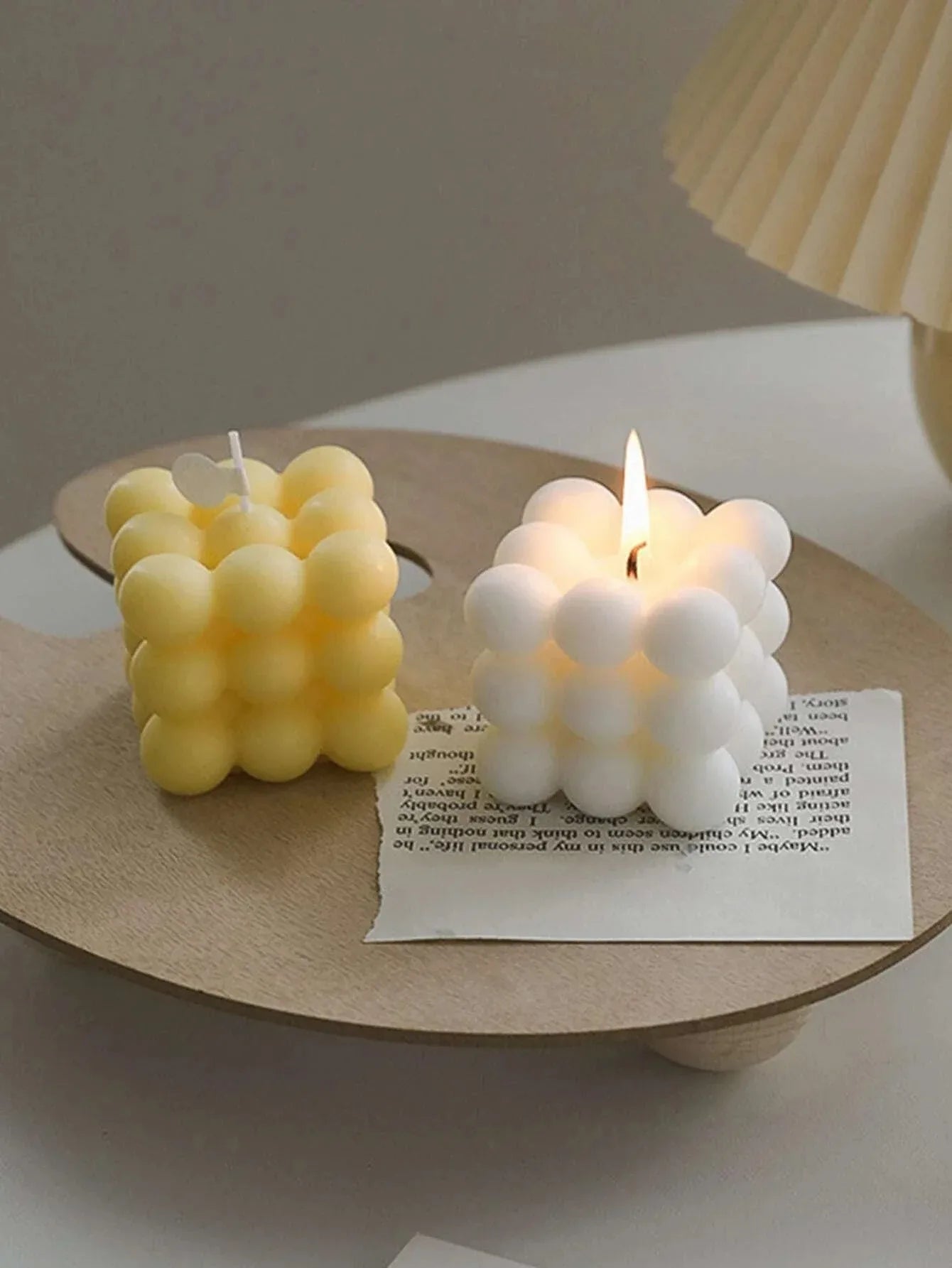 Two bubble-shaped candles on a wooden stand with a blurred background