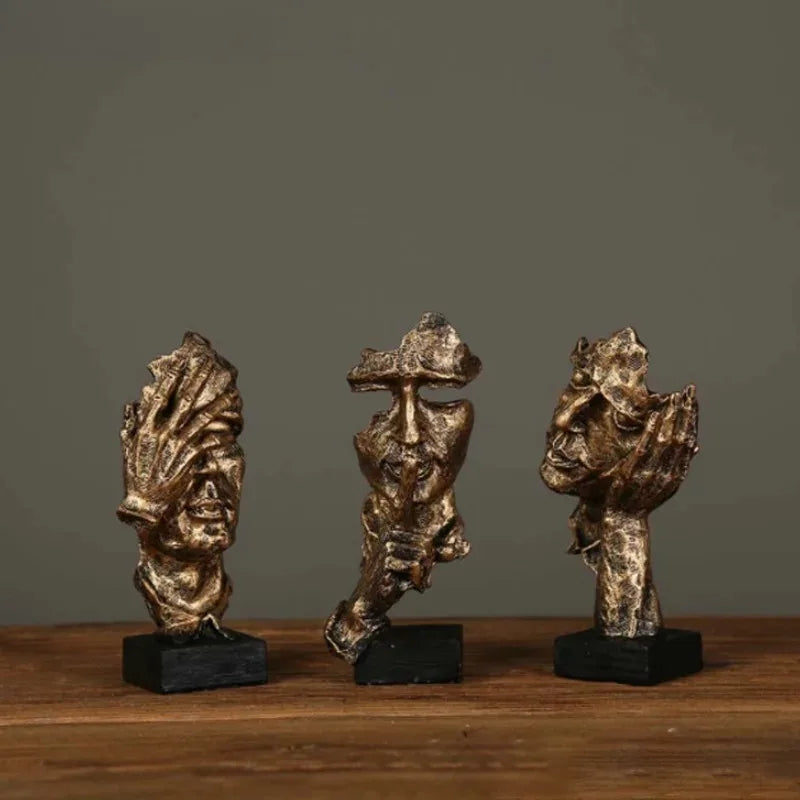 Three bronze figurines on a wooden surface with a dark background