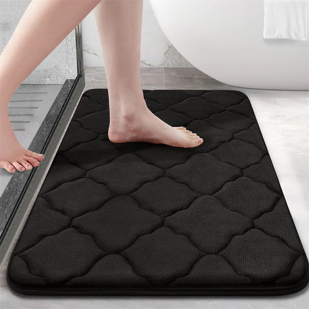 Black bath mat with a person stepping onto it in a bathroom setting.