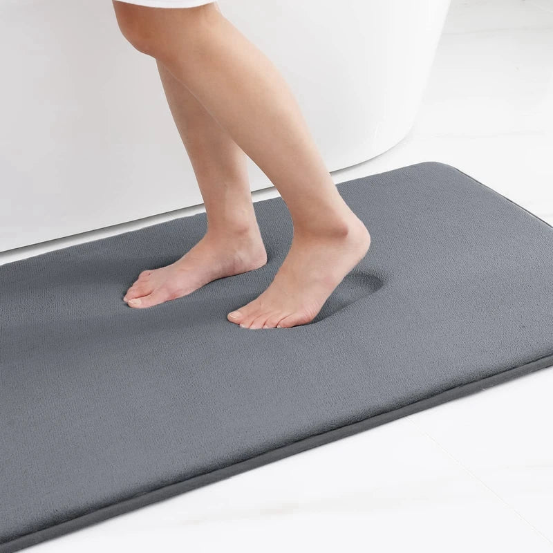 Person standing on a gray bath mat in a bathroom setting