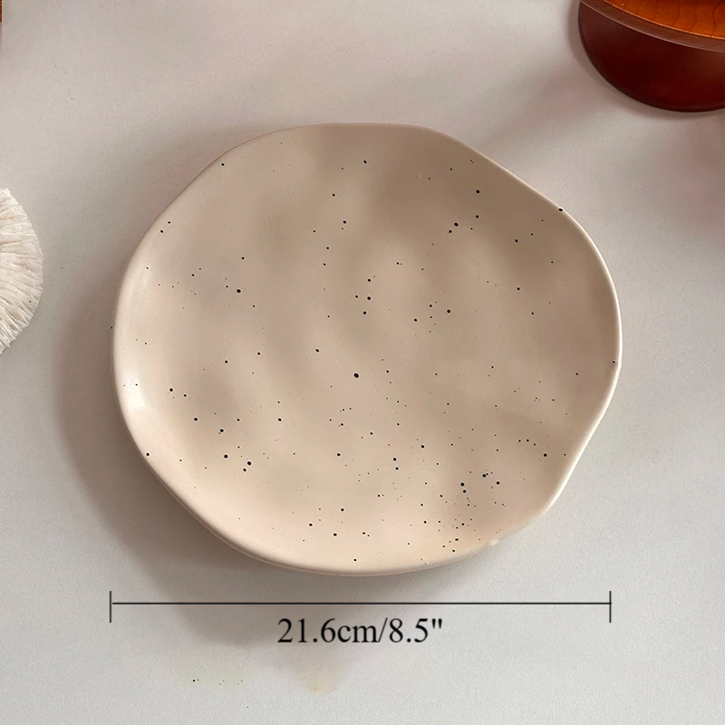 Beige ceramic plate with speckled texture on a light background, showing dimensions: Diameter 21.6cm