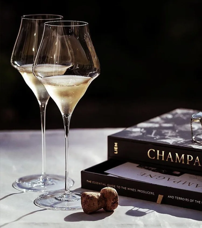 Two wine glasses with champagne on a table next to a book titled 'Champagne'.