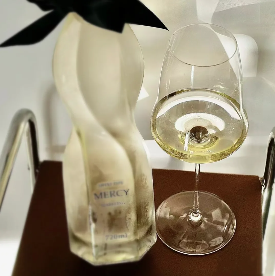 Mercy bottle and glass with white liquid on a dark surface