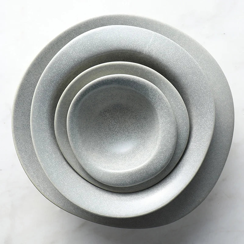 Set of four gray ceramic bowls stacked on a white background