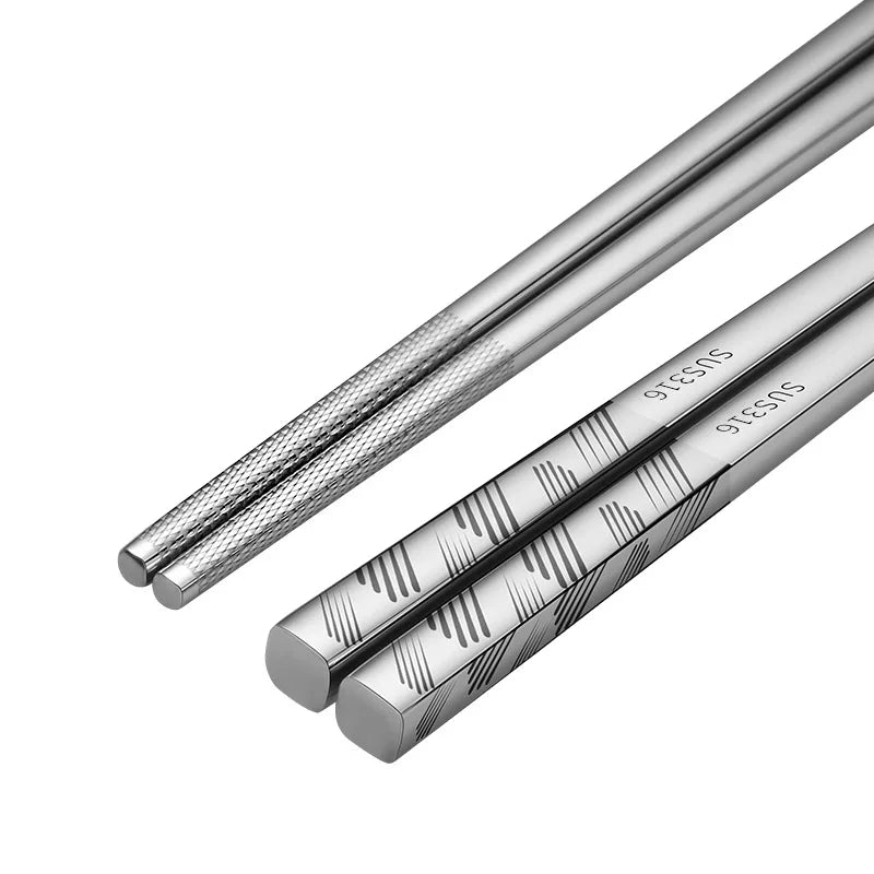 Two silver chopsticks with engraved patterns on a white background
