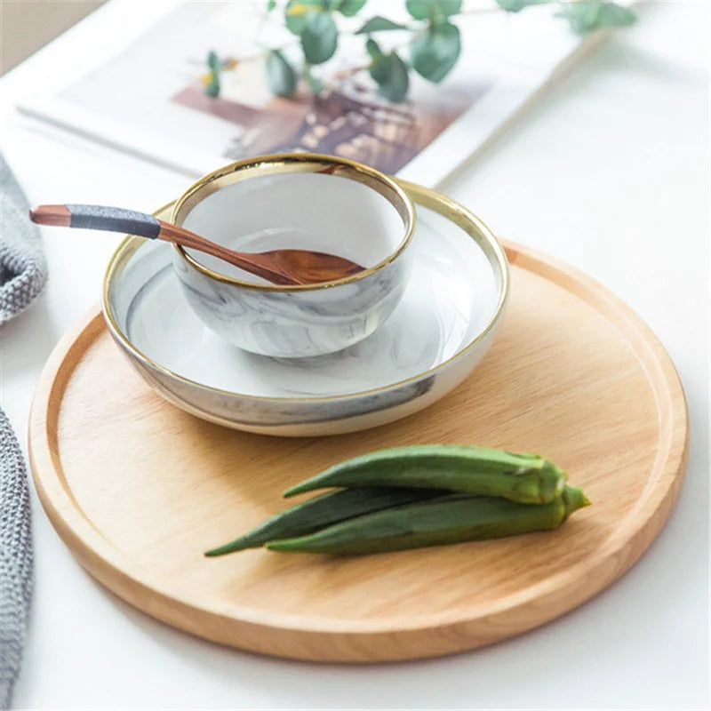Ceramic bowl with gold rim on a wooden tray with okra, on a light background