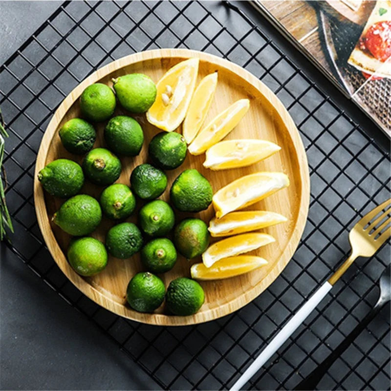 Wooden plate with green limes and sliced lemons on a dark grid background
