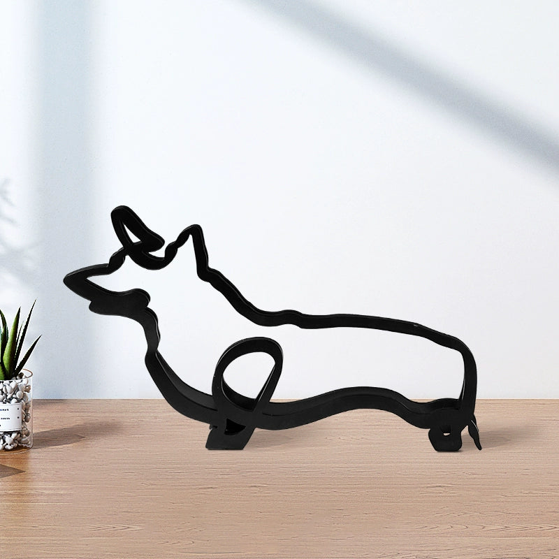 Black metal dog sculpture on a wooden surface with a white wall background