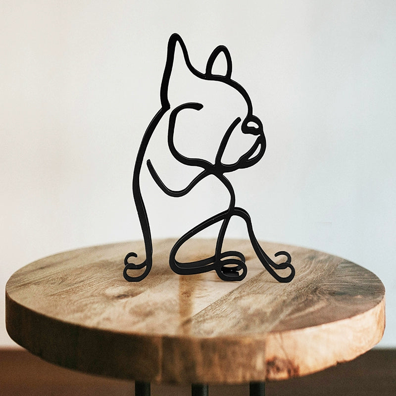 Black wire sculpture of a dog on a wooden table with a neutral background