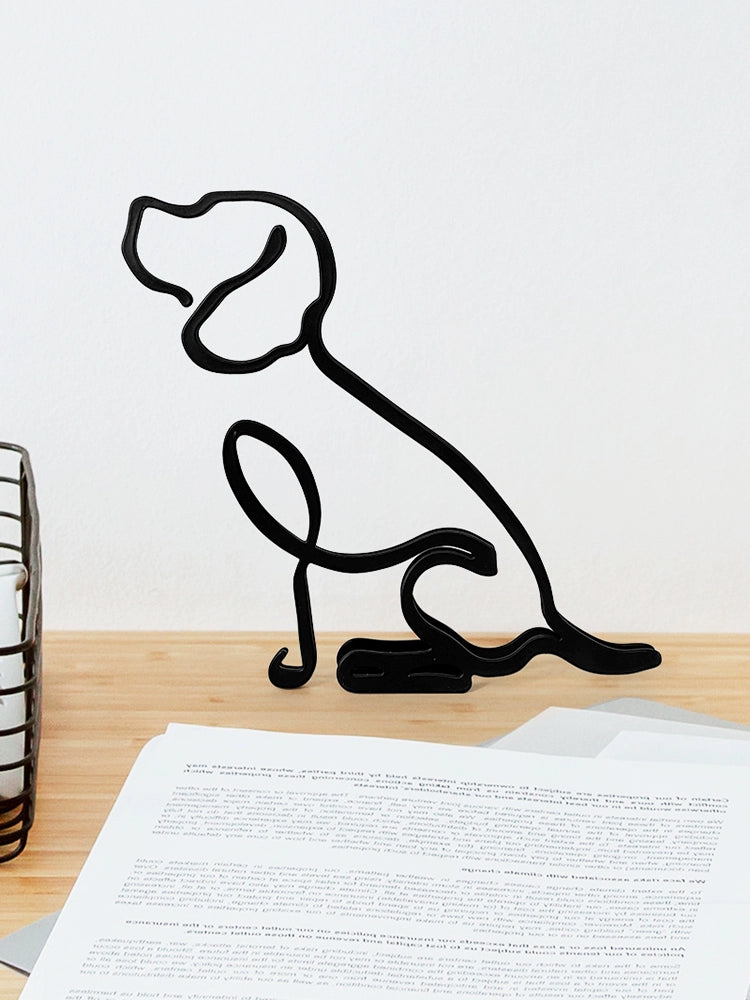 Black metal dog sculpture on a wooden surface with a white background