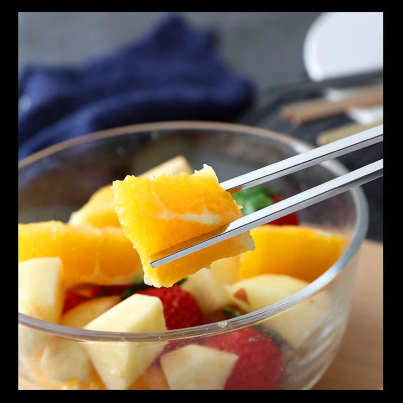 Fruit salad with a fork holding an orange slice above a bowl of fruit.