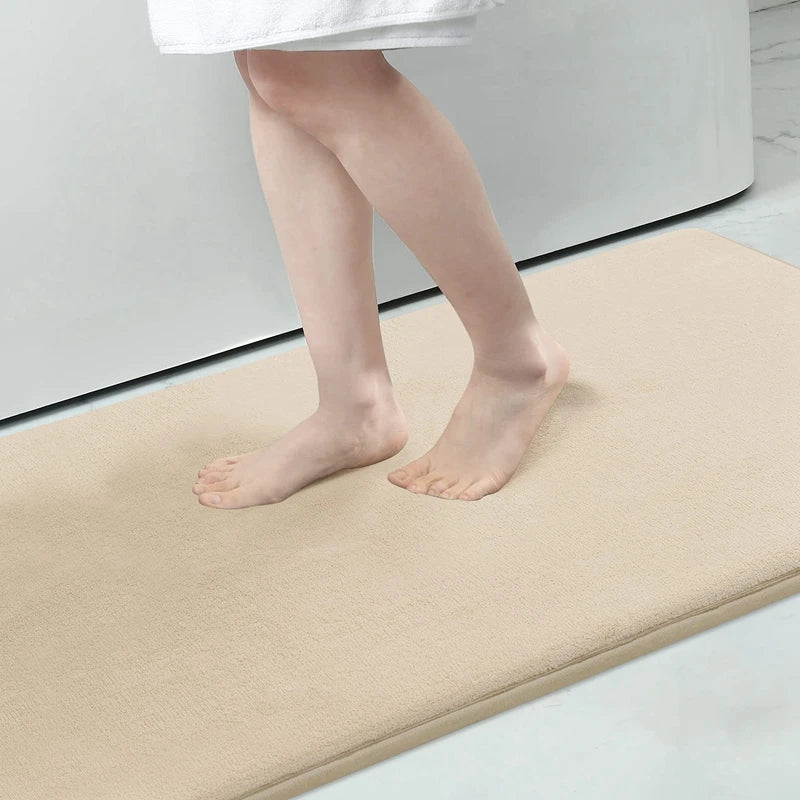Person standing on a beige bath mat in a bathroom setting