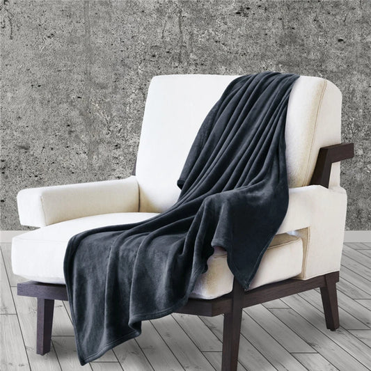White armchair with a dark gray blanket draped over it against a concrete wall.