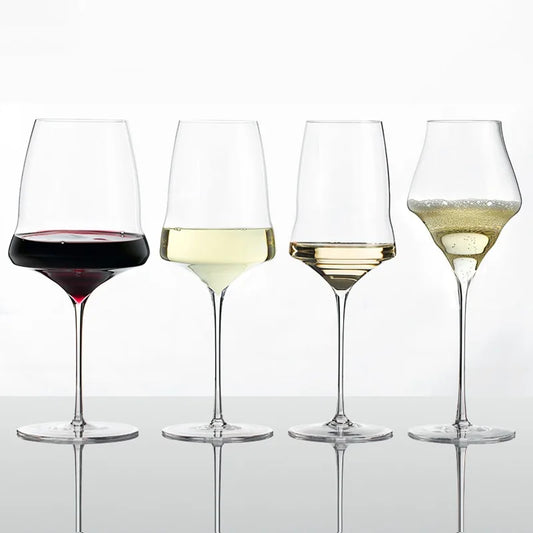 Four wine glasses with different types of wine on a reflective surface