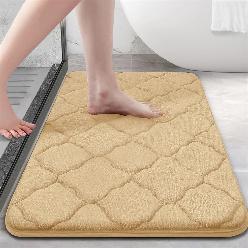 Beige bath mat on a bathroom floor with a person stepping onto it.