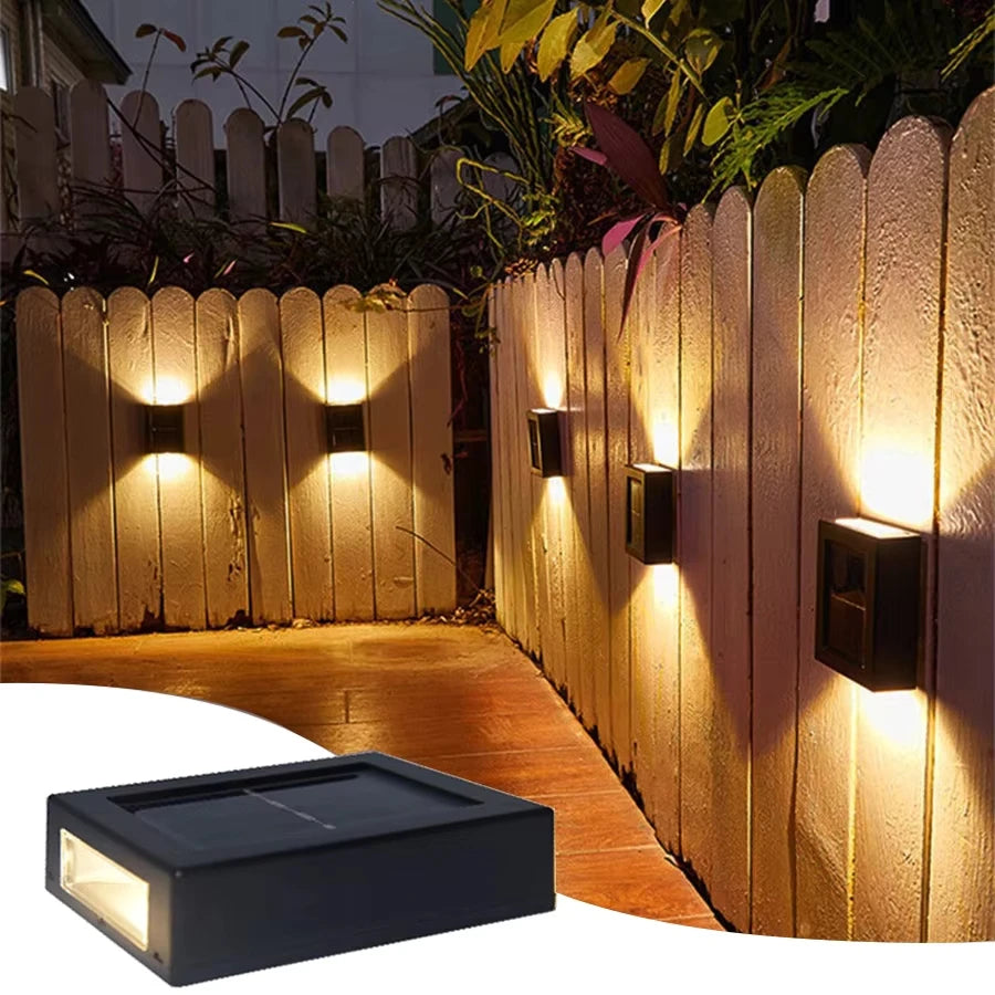 Solar-powered outdoor wall lights on a wooden fence with a clear view of the solar panel.