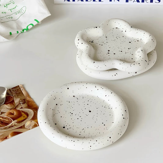 Two white ceramic bowls with black speckles on a light surface.