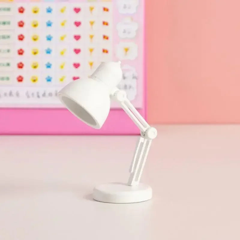 White desk lamp on a light pink surface with a colorful heart pattern in the background