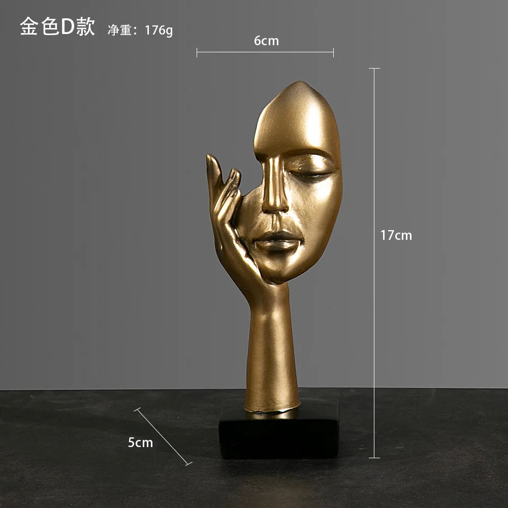 Gold abstract sculpture of a face and hand on a dark surface with: 5cm x 17cm x 6cm
