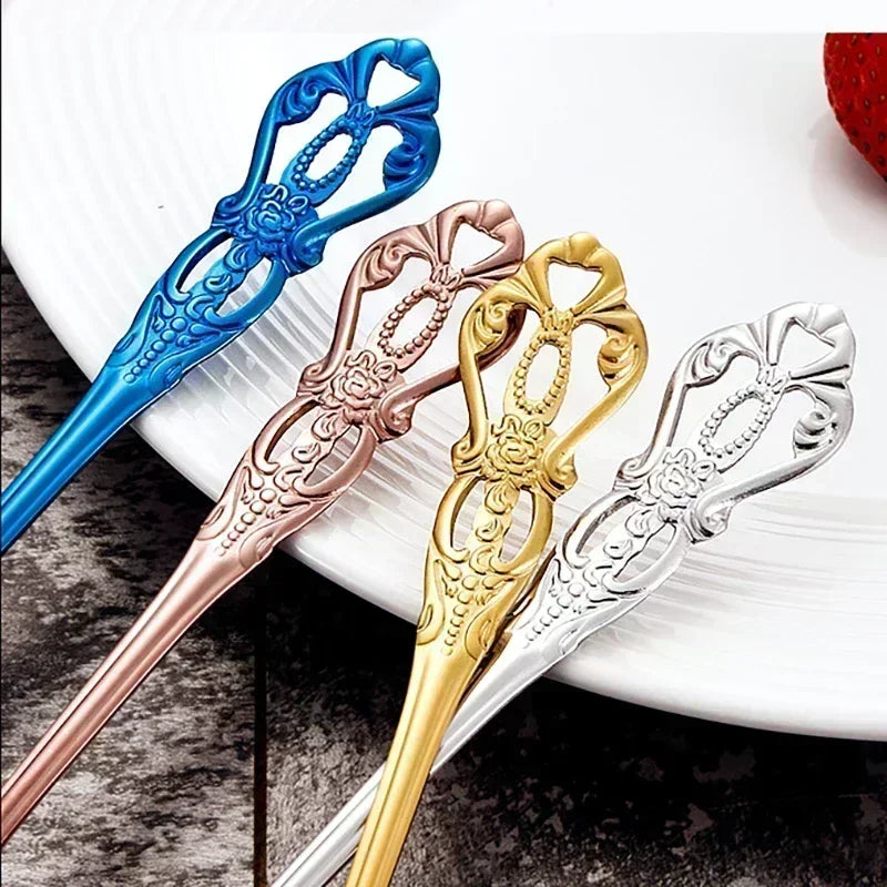 Four decorative cutlery handle tips in blue, rose gold, gold, and silver on a white plate.