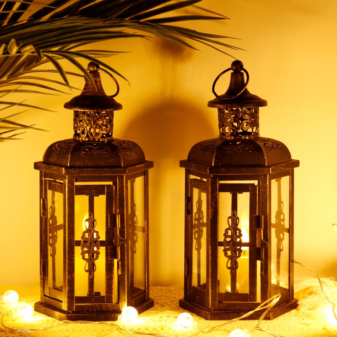 Two illuminated lanterns on a warm-toned background with string lights.