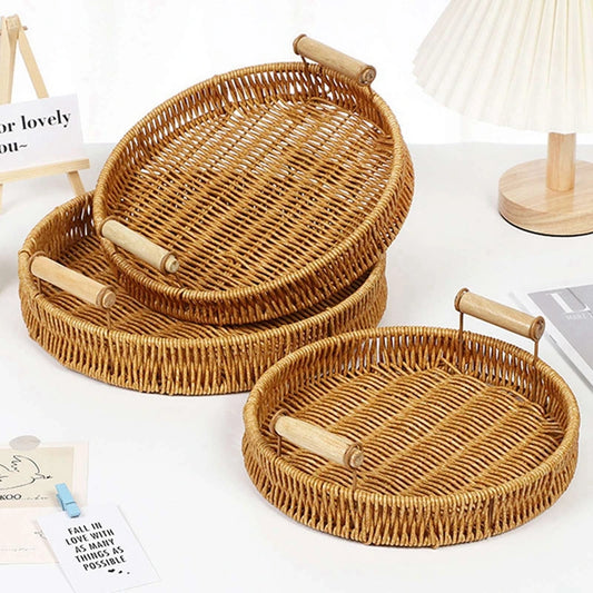 Set of three woven rattan trays with handles on a white surface.