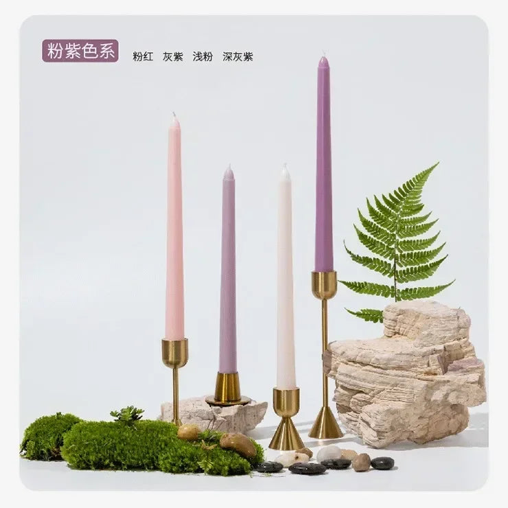 Decorative setup with purple candles, rocks, and plants on a light gray background