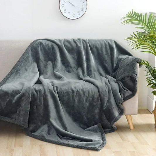 Gray blanket draped over a couch in a room with a clock and plant.