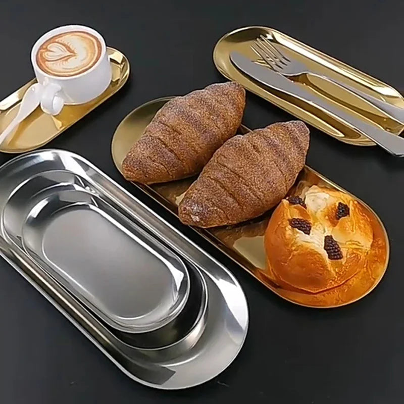 Metallic bread trays with bread and a coffee cup on a dark surface