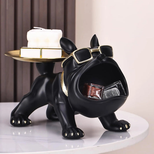 Black dog-shaped figurine with sunglasses holding a box on a white surface.
