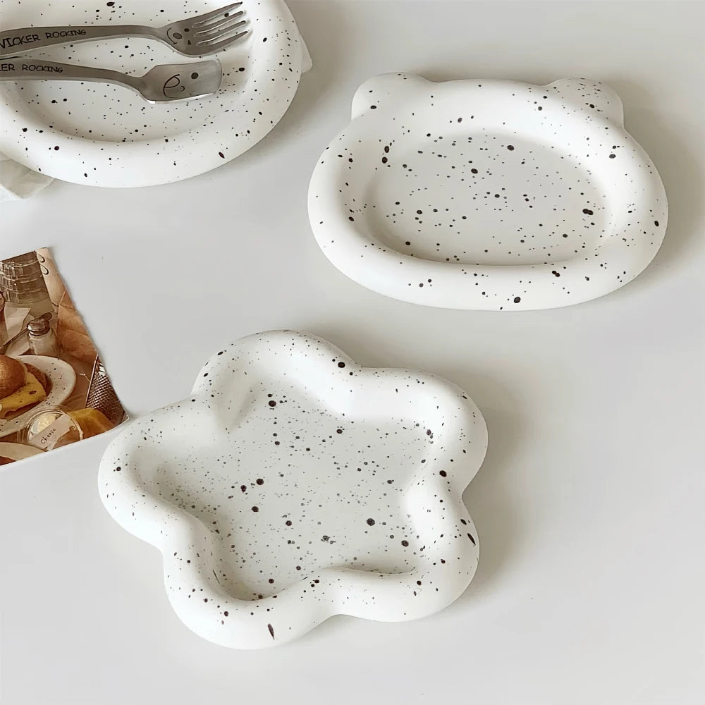 Speckled ceramic plates with unique shapes on a white surface