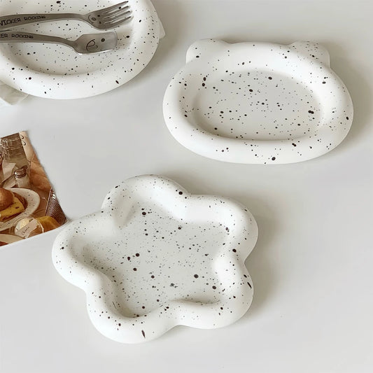 Speckled ceramic plates with unique shapes on a white surface