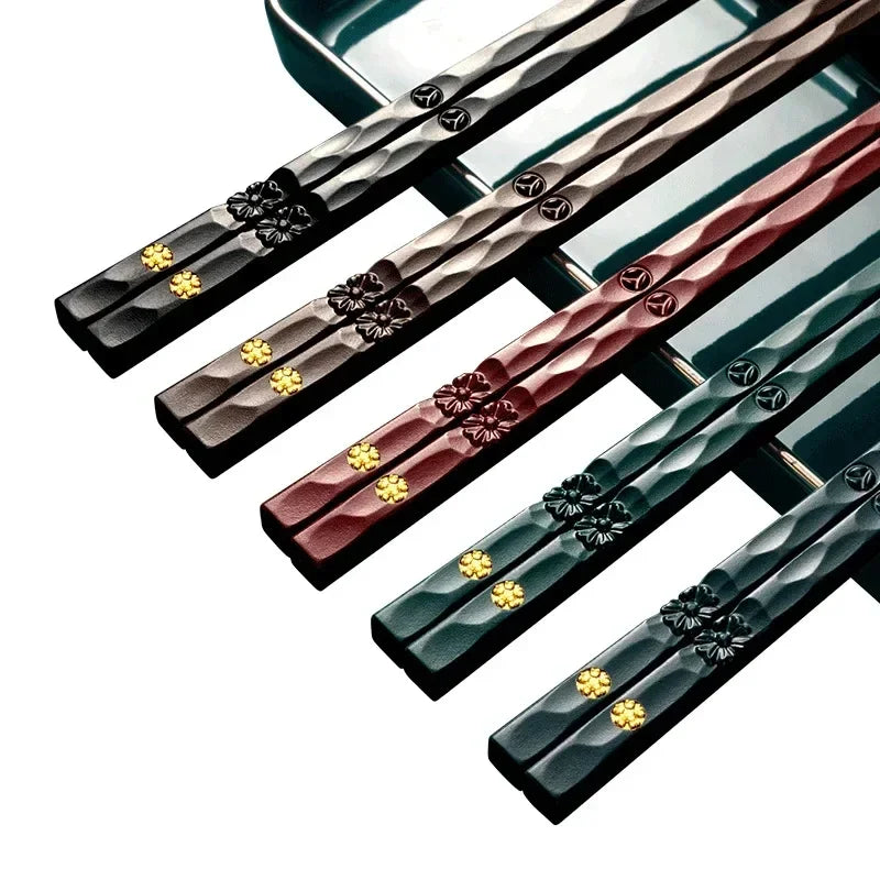 Set of five unique color pairs of decorative chopsticks with floral designs on a white background