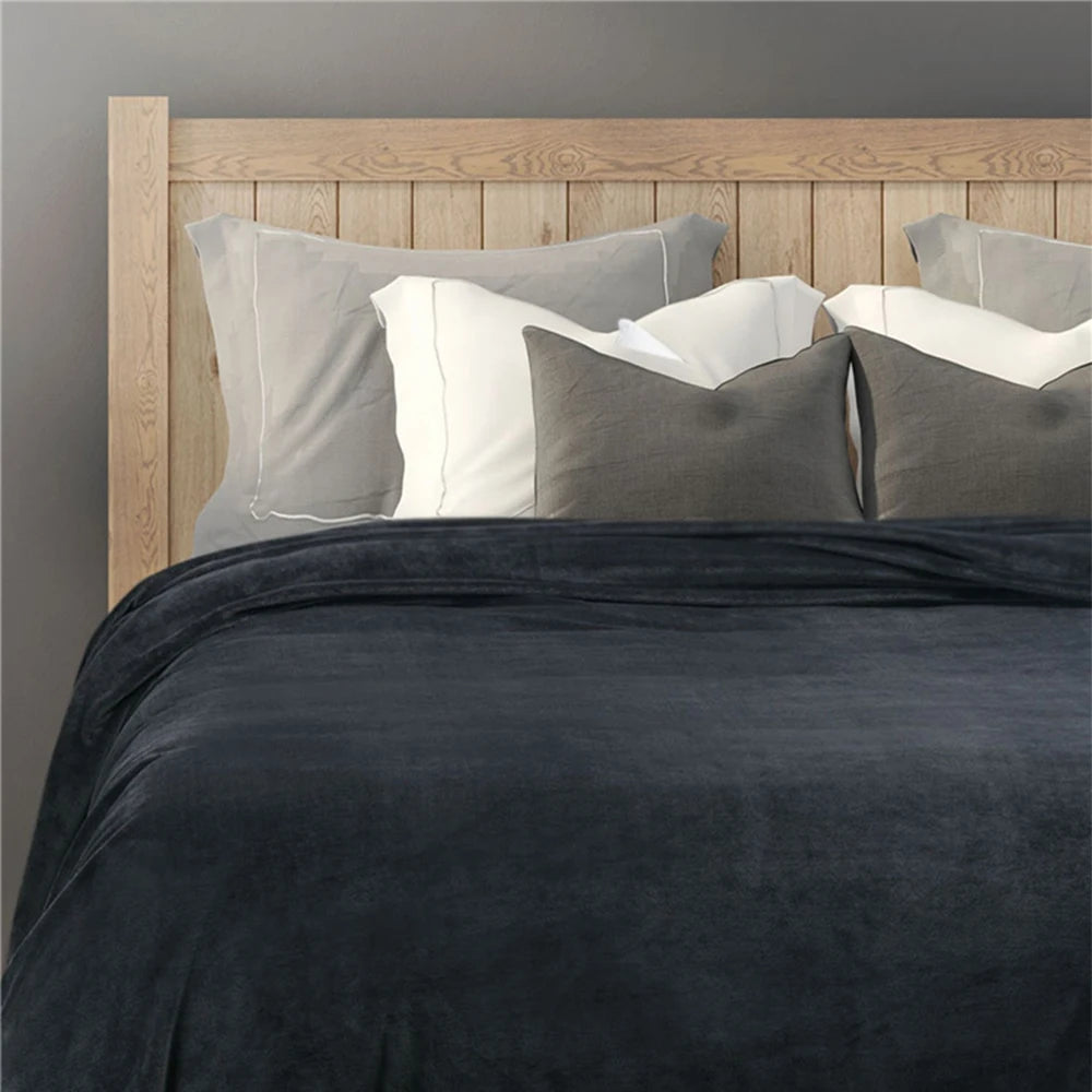 Bed with dark gray comforter and pillows against a wooden headboard.