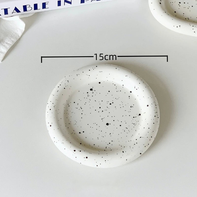 Speckled ceramic plate on a white surface with measurement: 15cm