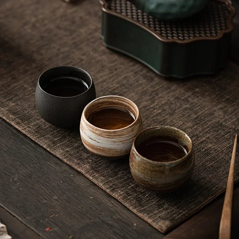 Three ceramic cups on a textured surface with a blurred background