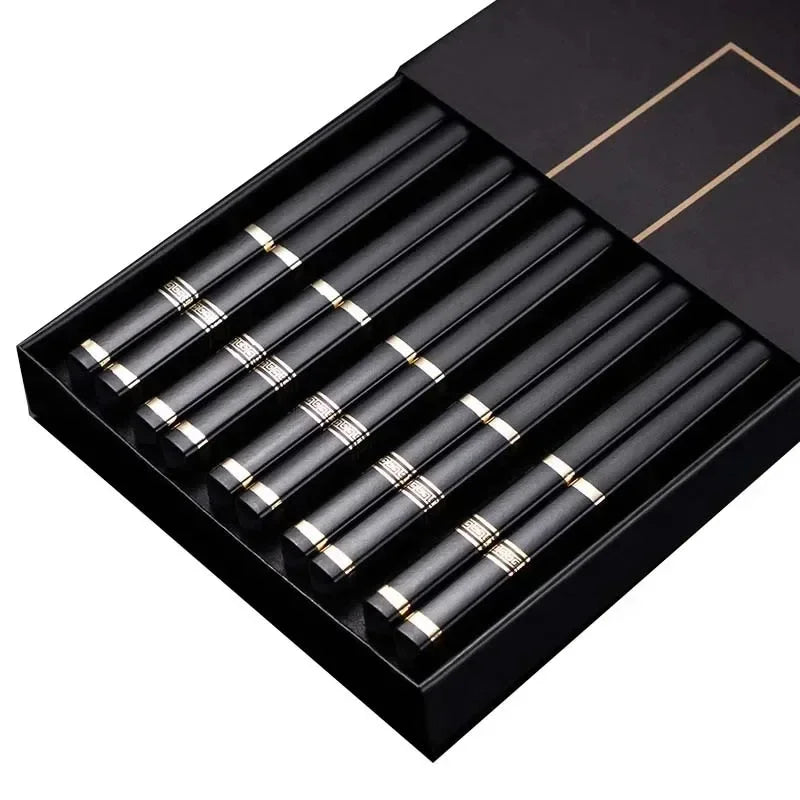 Set of black and gold chopsticks in a black box on a white background