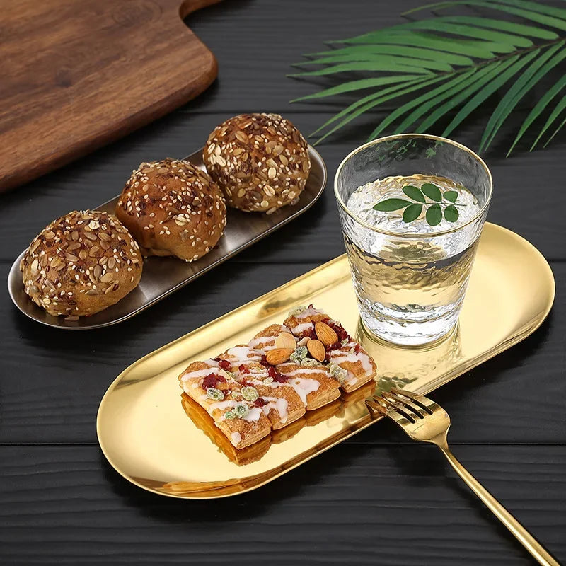 Gold tray with pastries and a glass of water on a dark surface