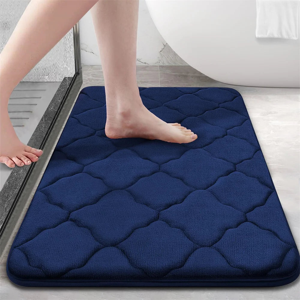 Navy blue bath mat with a person stepping onto it in a bathroom setting.
