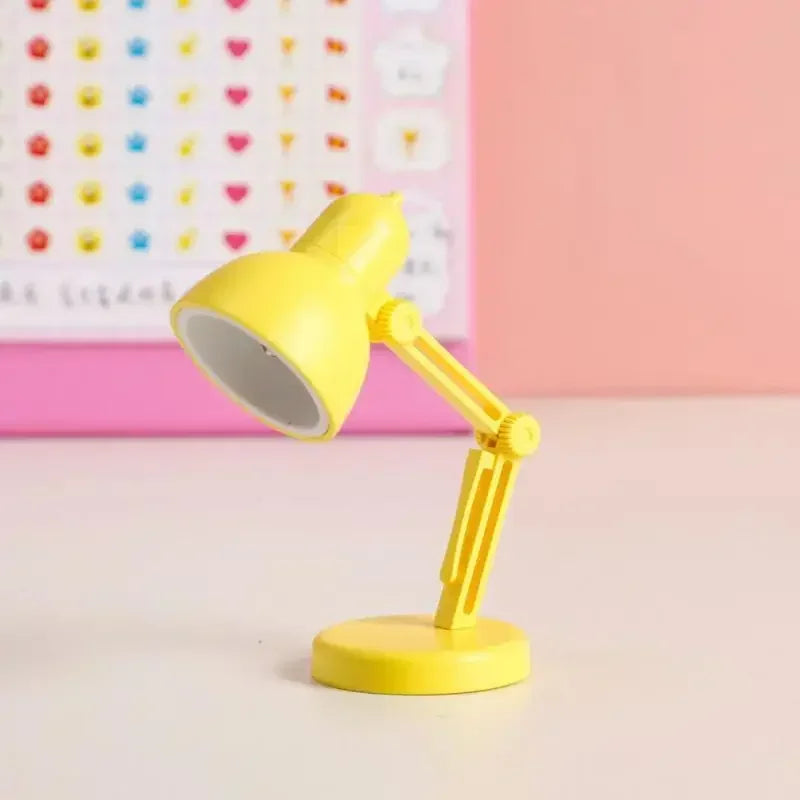 Yellow desk lamp on a light pink surface with a colorful heart patterned wall in the background.